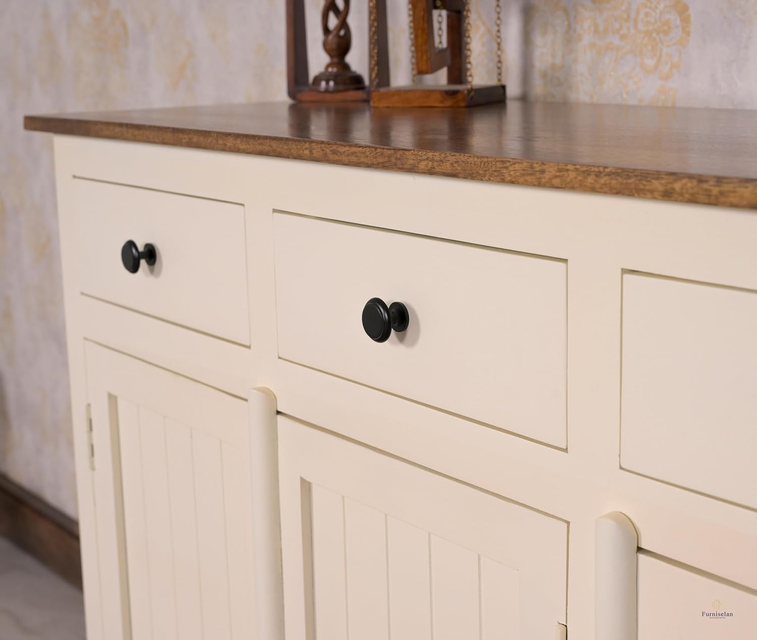 Beige cabinet with black knobs against a patterned wall.