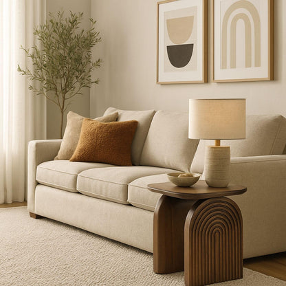 Beige sofa with decorative pillows and a wooden side table in a living room setting.