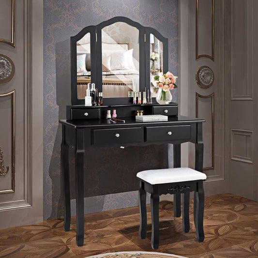 Black vanity table with mirror and stool in a room with decorative wallpaper.