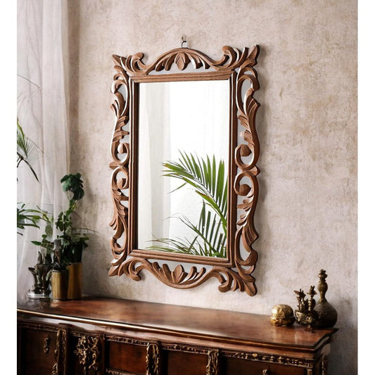 Decorative wooden mirror with intricate carvings on a wall above a wooden console table.
