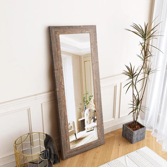 Wooden floor mirror in a room with a plant and decorative items.