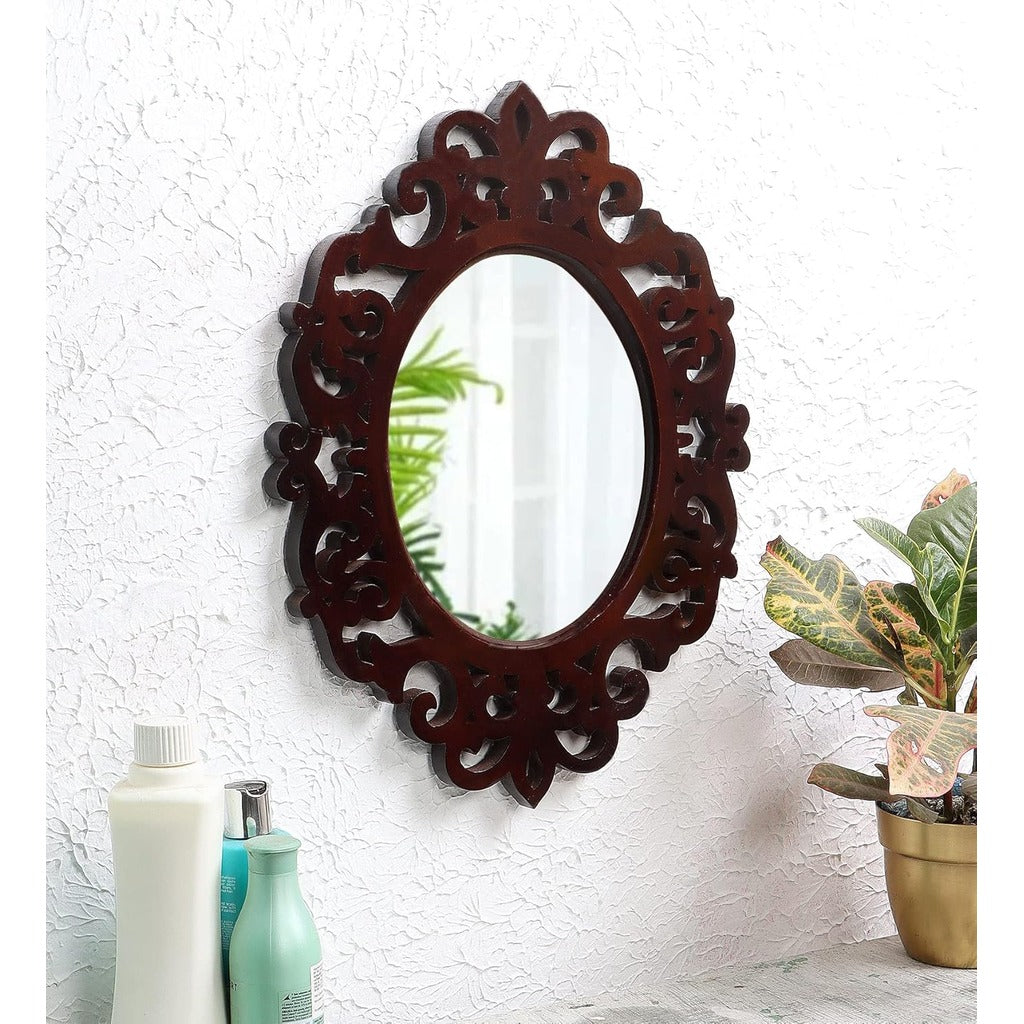 Decorative oval mirror with intricate wooden frame on a textured white wall.