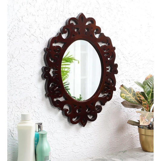 Decorative oval mirror with intricate wooden frame on a textured white wall.