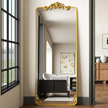 Full-length mirror with gold frame in a room with a bed and window.