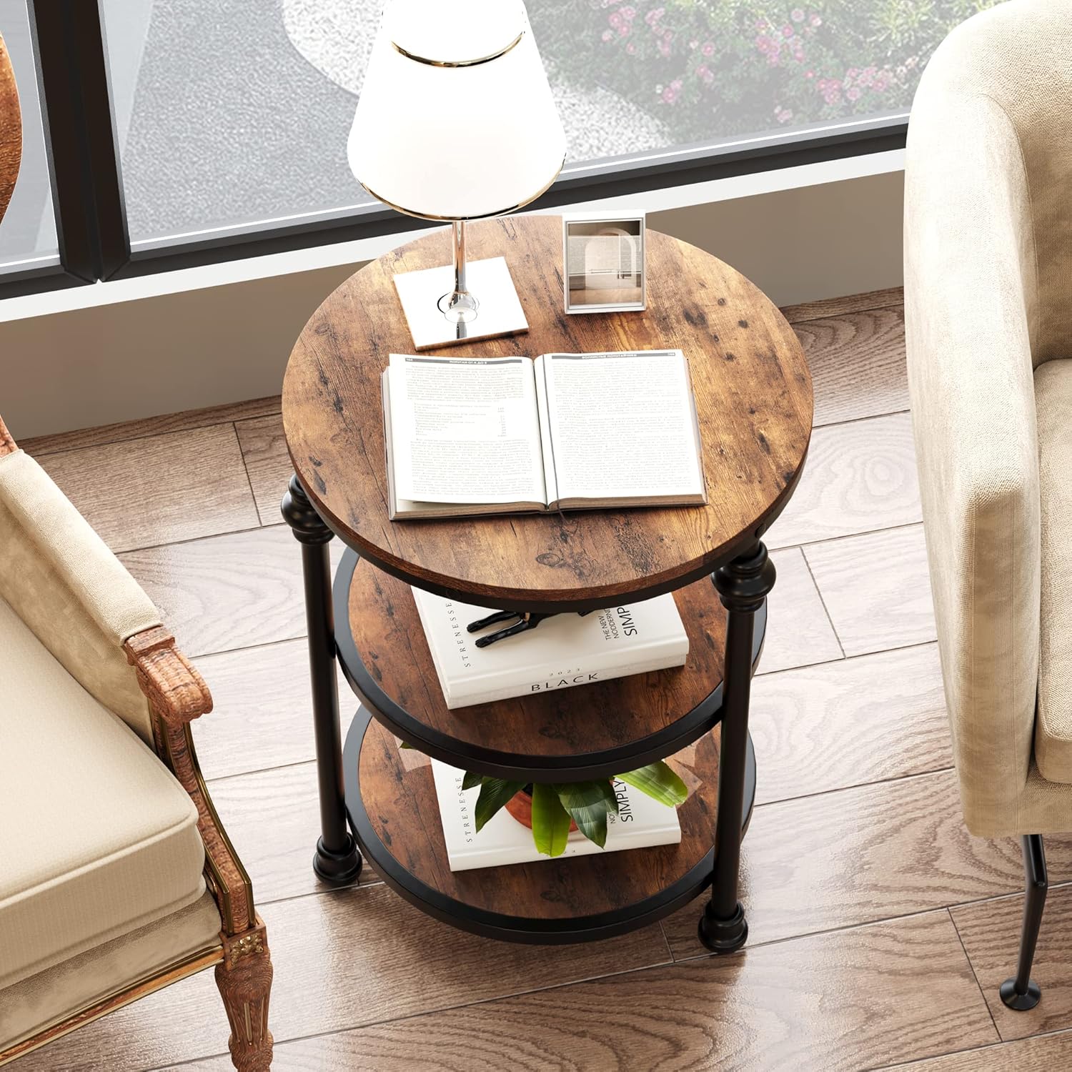 Round wooden side table with books and a lamp in a living room setting.