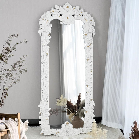 Decorative white mirror with floral patterns in a room setting.