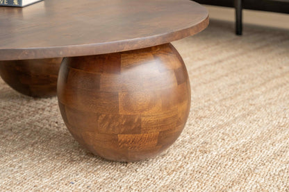 Wooden coffee table with spherical bases on a carpeted floor