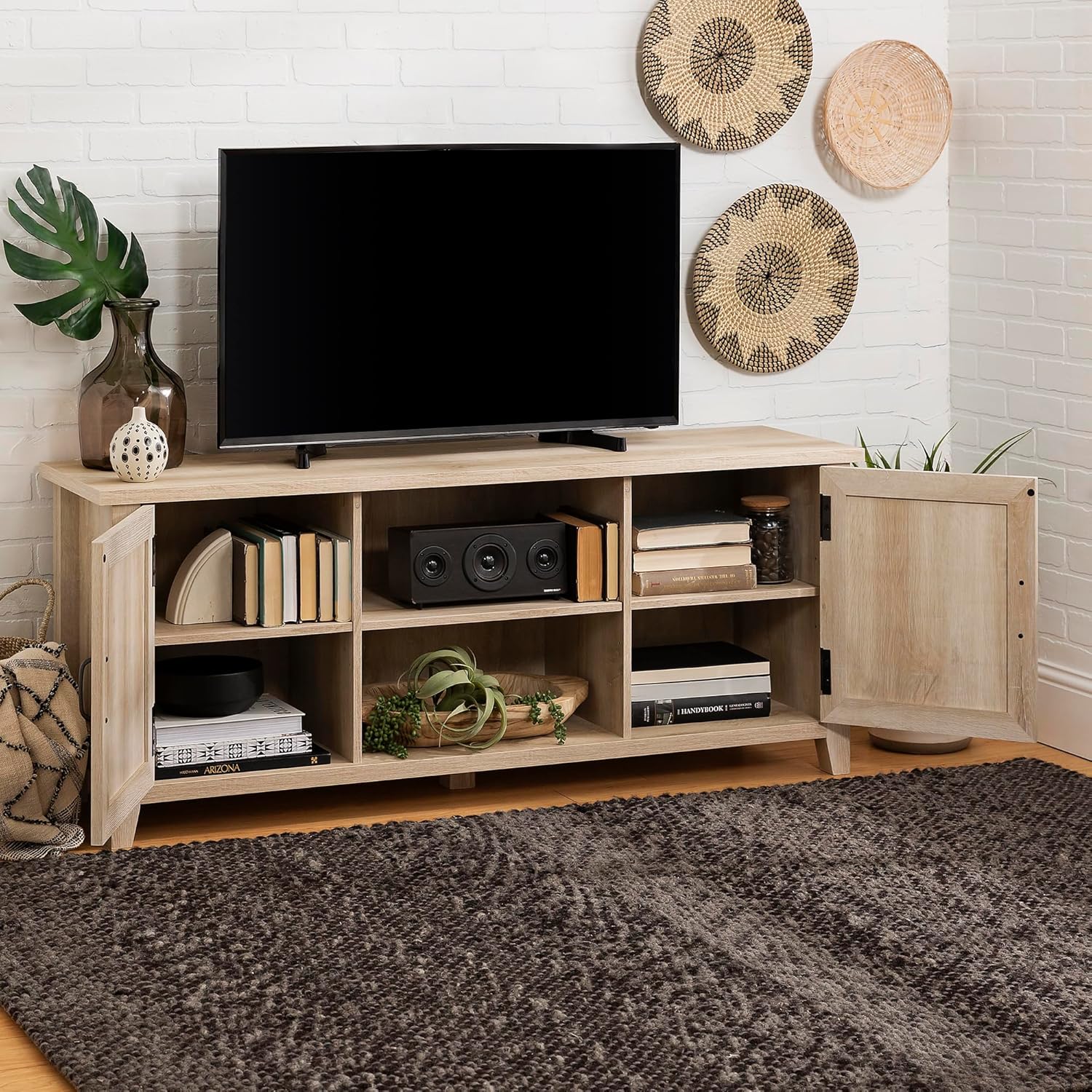 Wooden TV stand with a television, speakers, and decorative items in a living room setting.