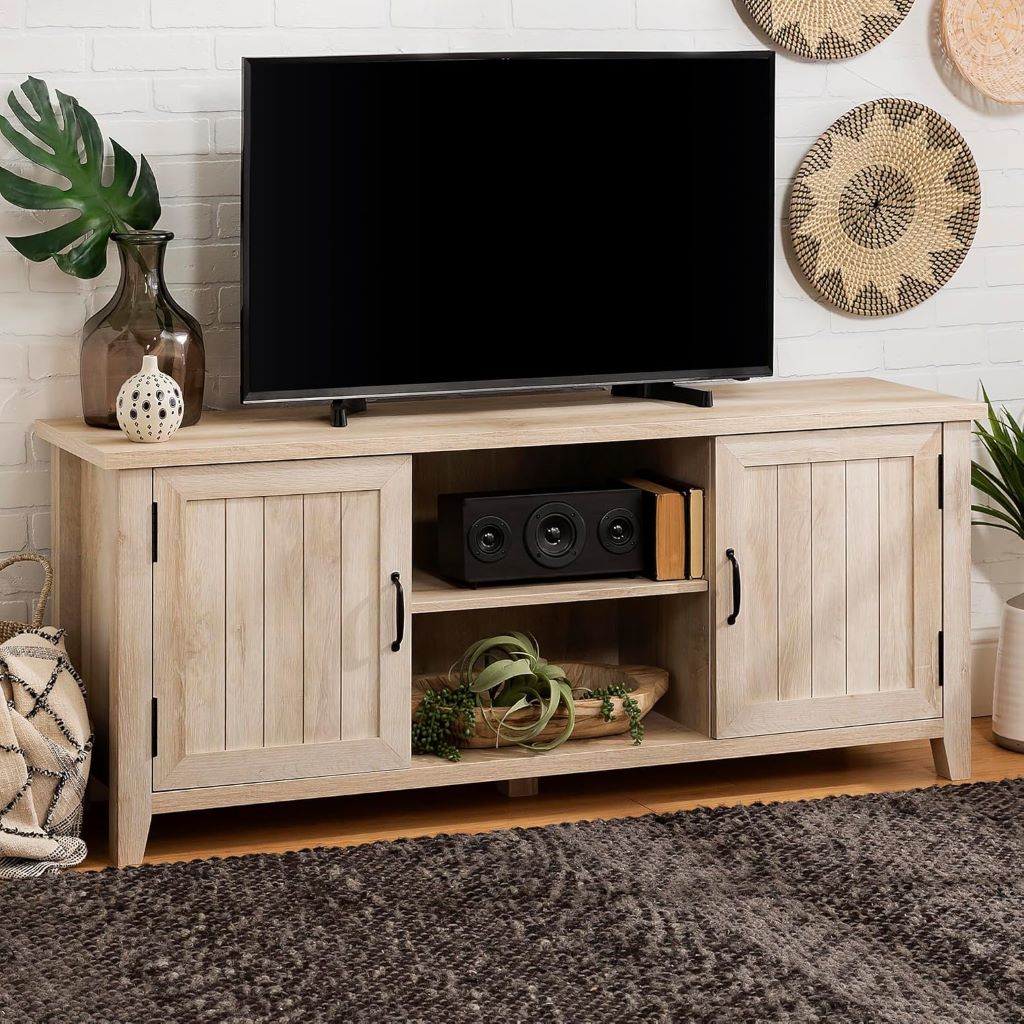 Light wood TV stand with a television on top, speakers below, and decorative items around.