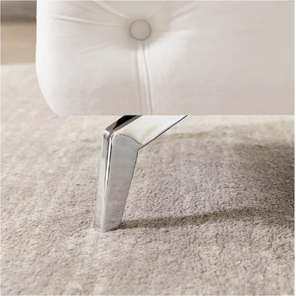 Close-up of a white upholstered chair with a chrome leg on a beige carpet.