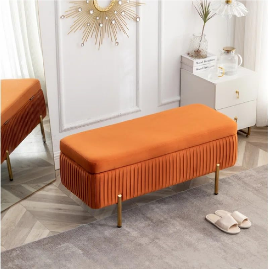 Orange bench with pleated design in a room setting with a white wall and decorative elements.