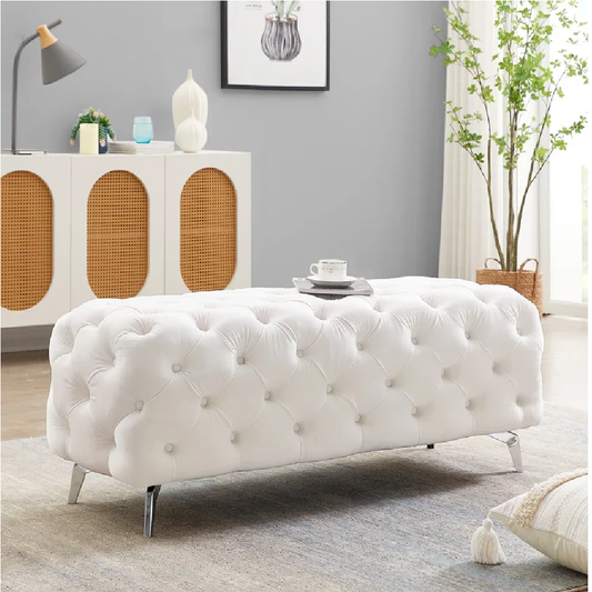 White tufted bench in a living room setting with a gray wall and decorative items.