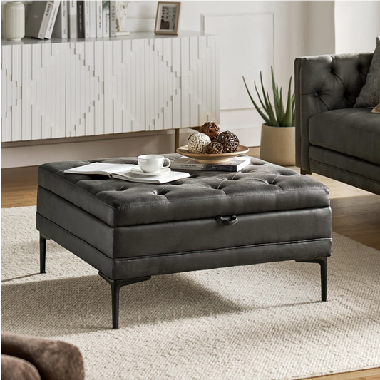 Gray tufted ottoman in a living room setting with a coffee table and decor items.