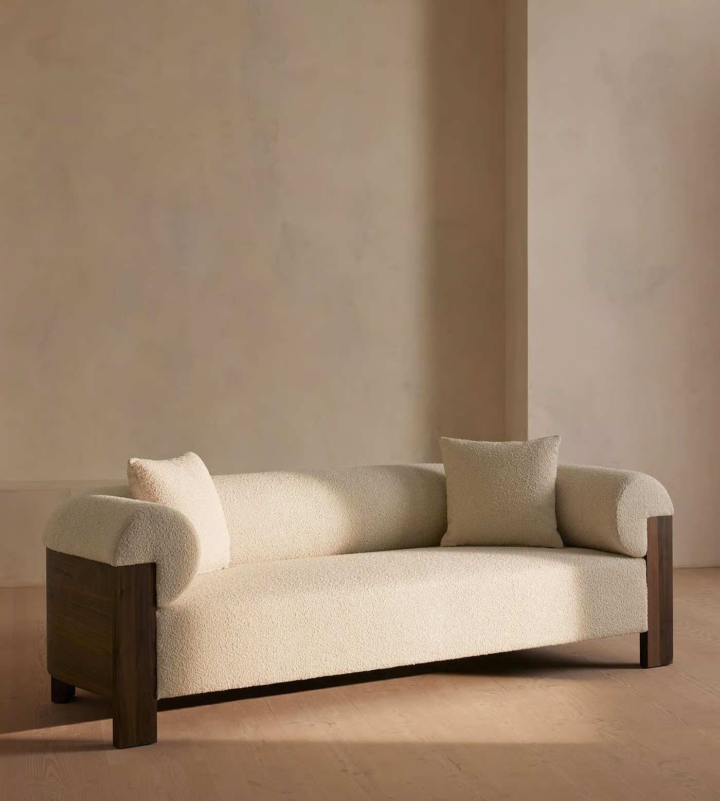 Beige sofa with wooden legs against a beige wall