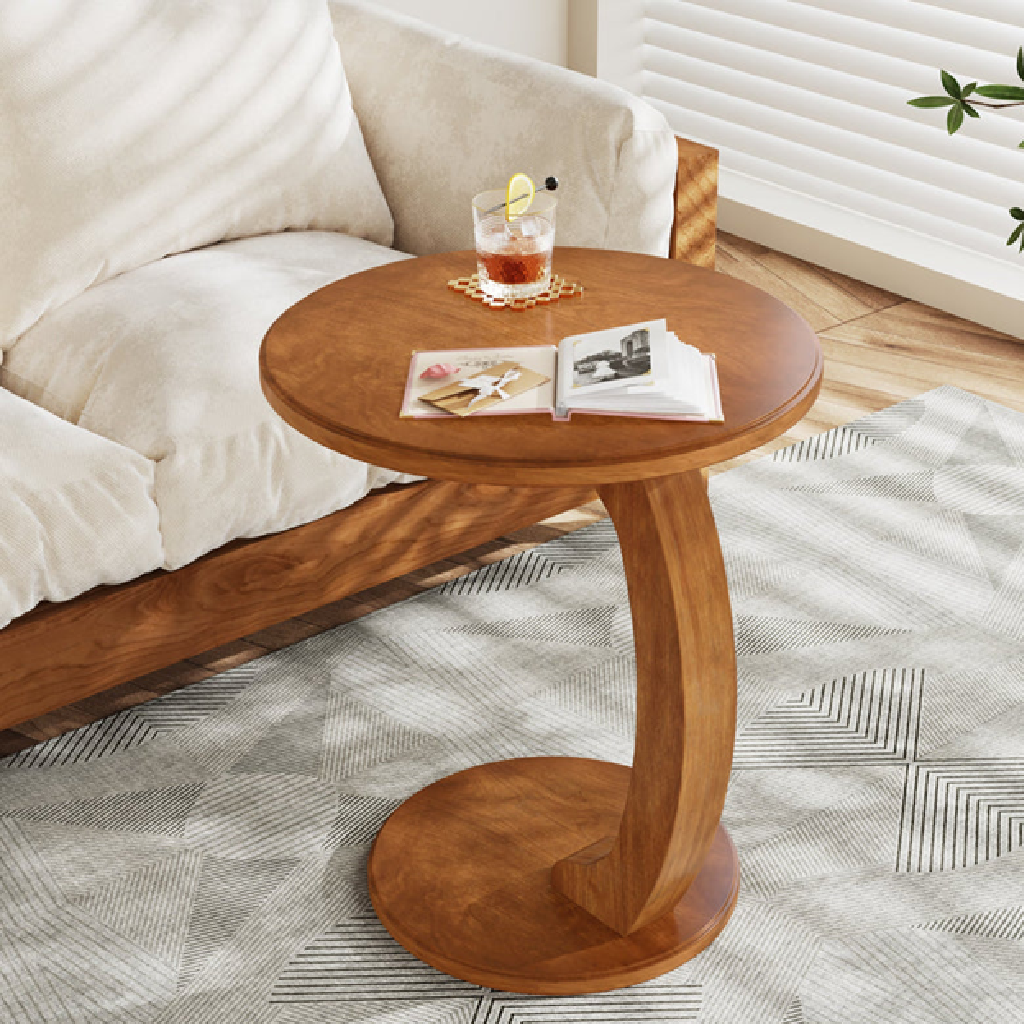 Wooden side table with a glass of tea and magazines next to a sofa.