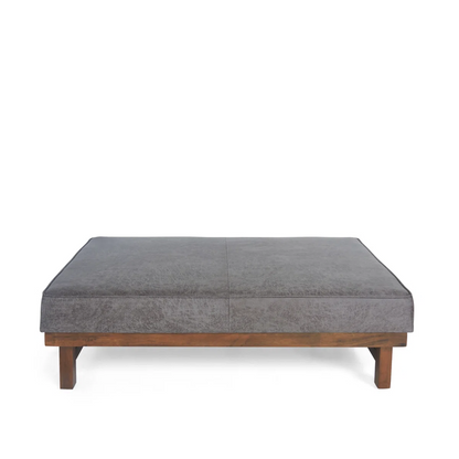 Gray upholstered ottoman with wooden legs on a white background