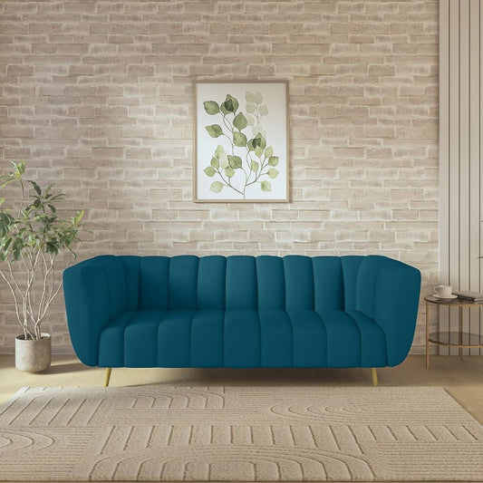 Blue sofa in a room with a brick wall, framed artwork, and plant.