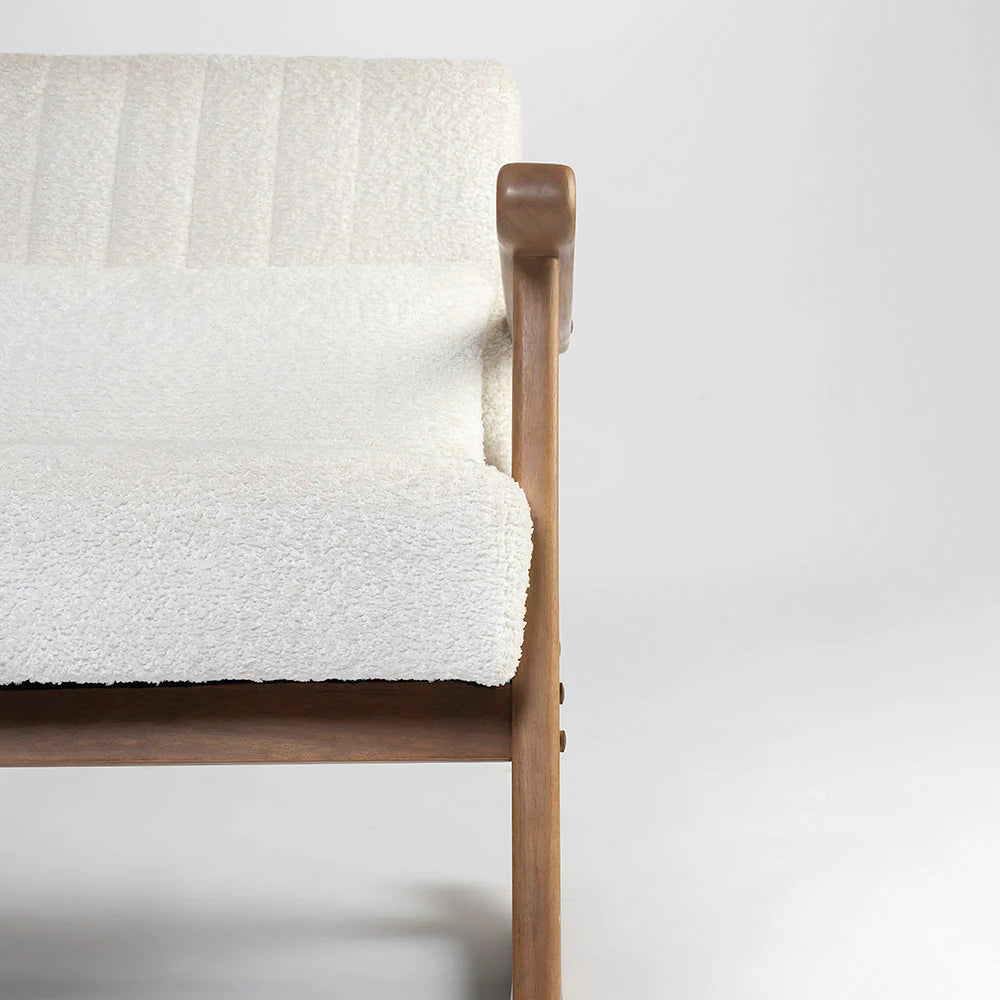 Wooden chair with a white textured blanket draped over it on a plain background