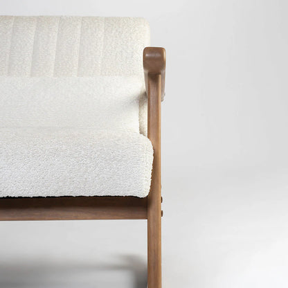 Wooden chair with a white textured blanket draped over it on a plain background