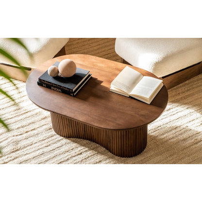 Wooden coffee table with books and decorative items in a sunlit room