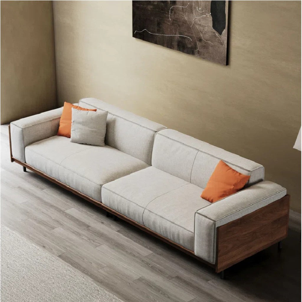 Gray sofa with orange cushions in a room with a beige wall and abstract painting.