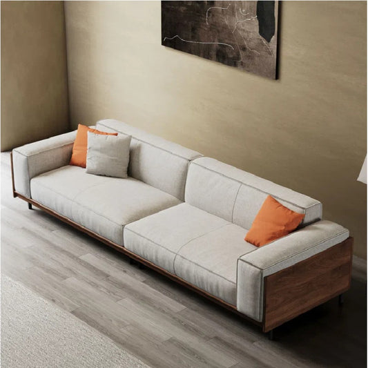 Gray sofa with orange cushions in a room with a beige wall and abstract painting.