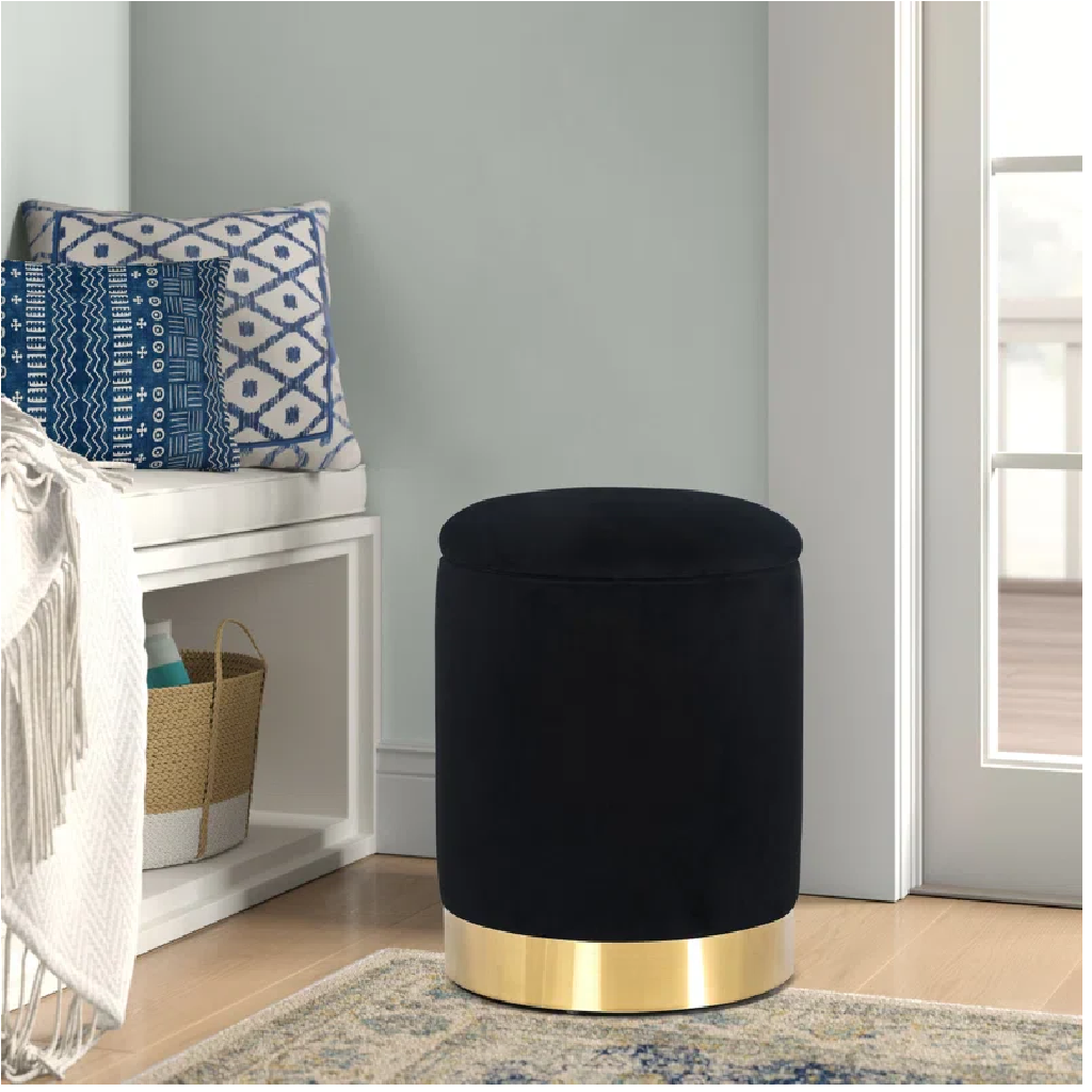 Black ottoman with gold base in a room setting
