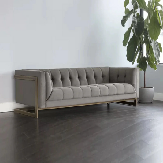 Gray tufted sofa in a minimalistic room with a plant