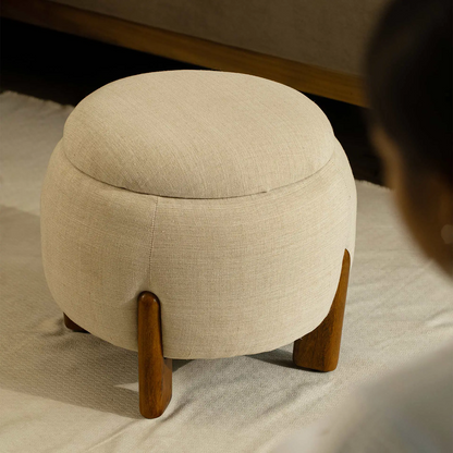 Beige ottoman with wooden legs on a light-colored floor