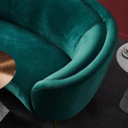 Teal velvet armchair with a gold side table in a room setting.