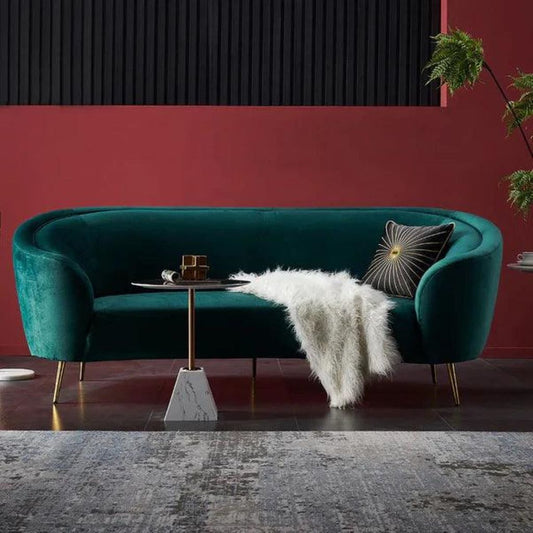 Teal velvet sofa with decorative items in a modern living room setting.