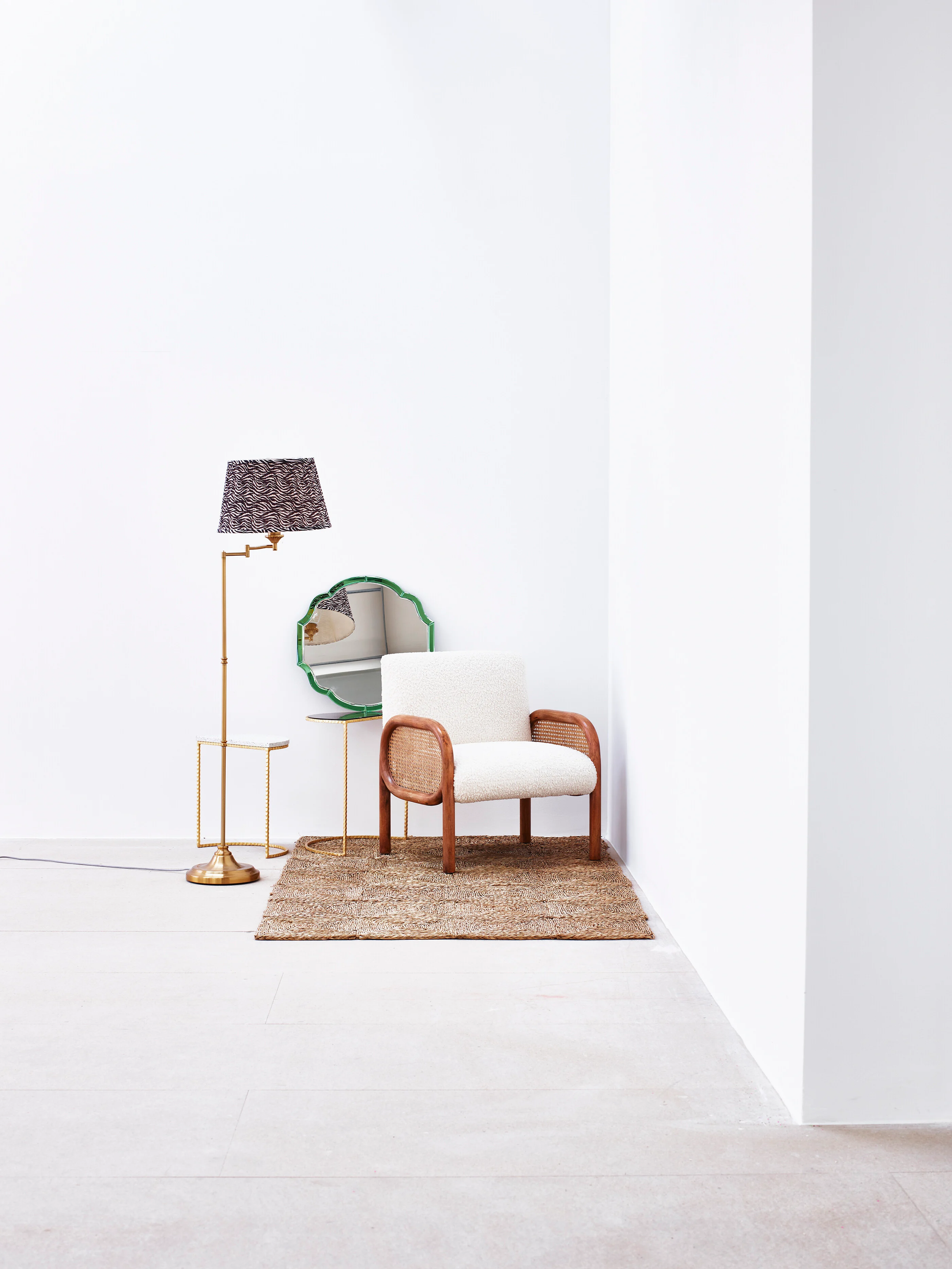 Minimalist living room with a white armchair, floor lamp, and round mirror.