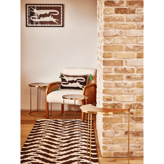 Living room with wicker chair, zebra print rug, and brick wall.