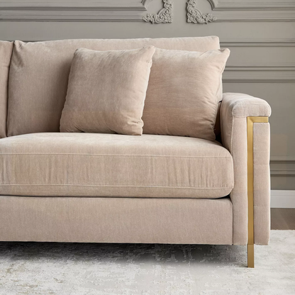 Beige sofa with gold legs in a room with decorative wall molding.