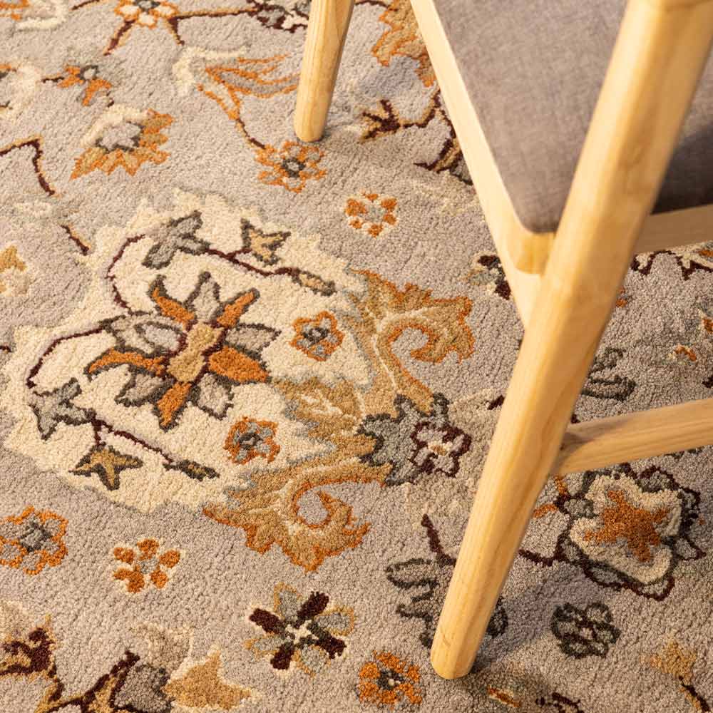 Close-up of a floral-patterned rug with a chair leg on a textured surface