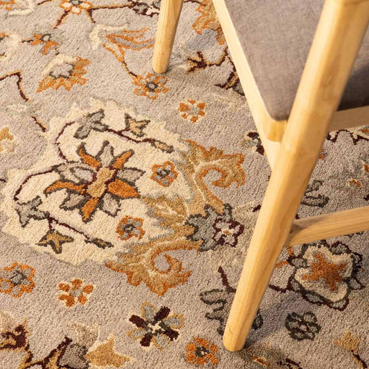 Close-up of a floral-patterned rug with a chair leg on a textured surface