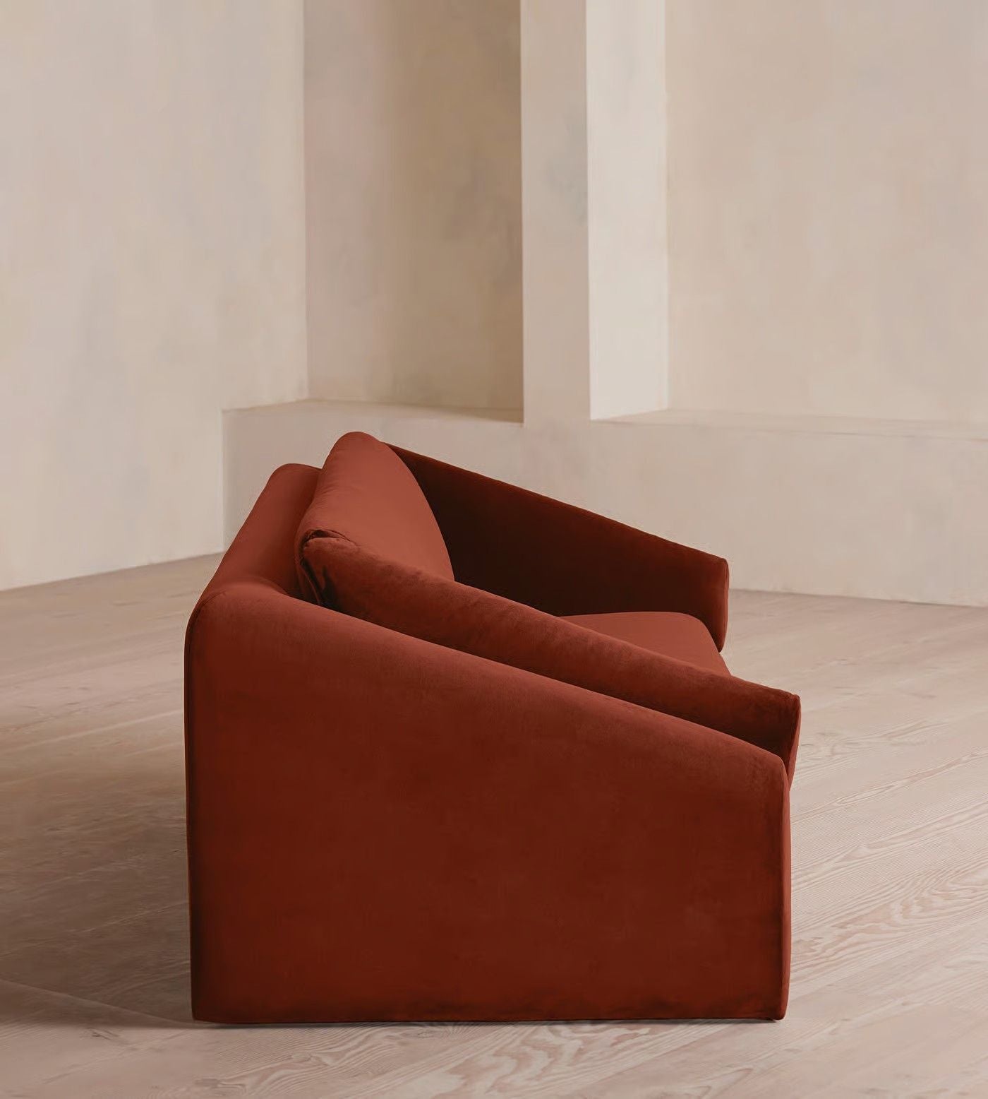 Brown sofa in a minimalistic room with light-colored walls and floor.
