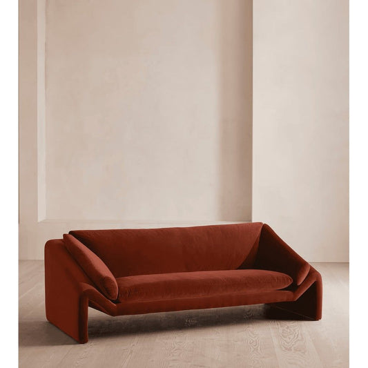 Brown sofa in a minimalistic room with beige walls and floor.