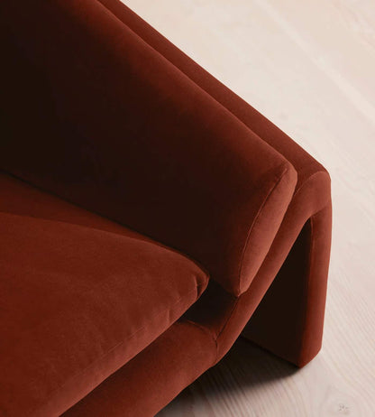 Close-up of a brown velvet sofa corner on a light wooden floor.