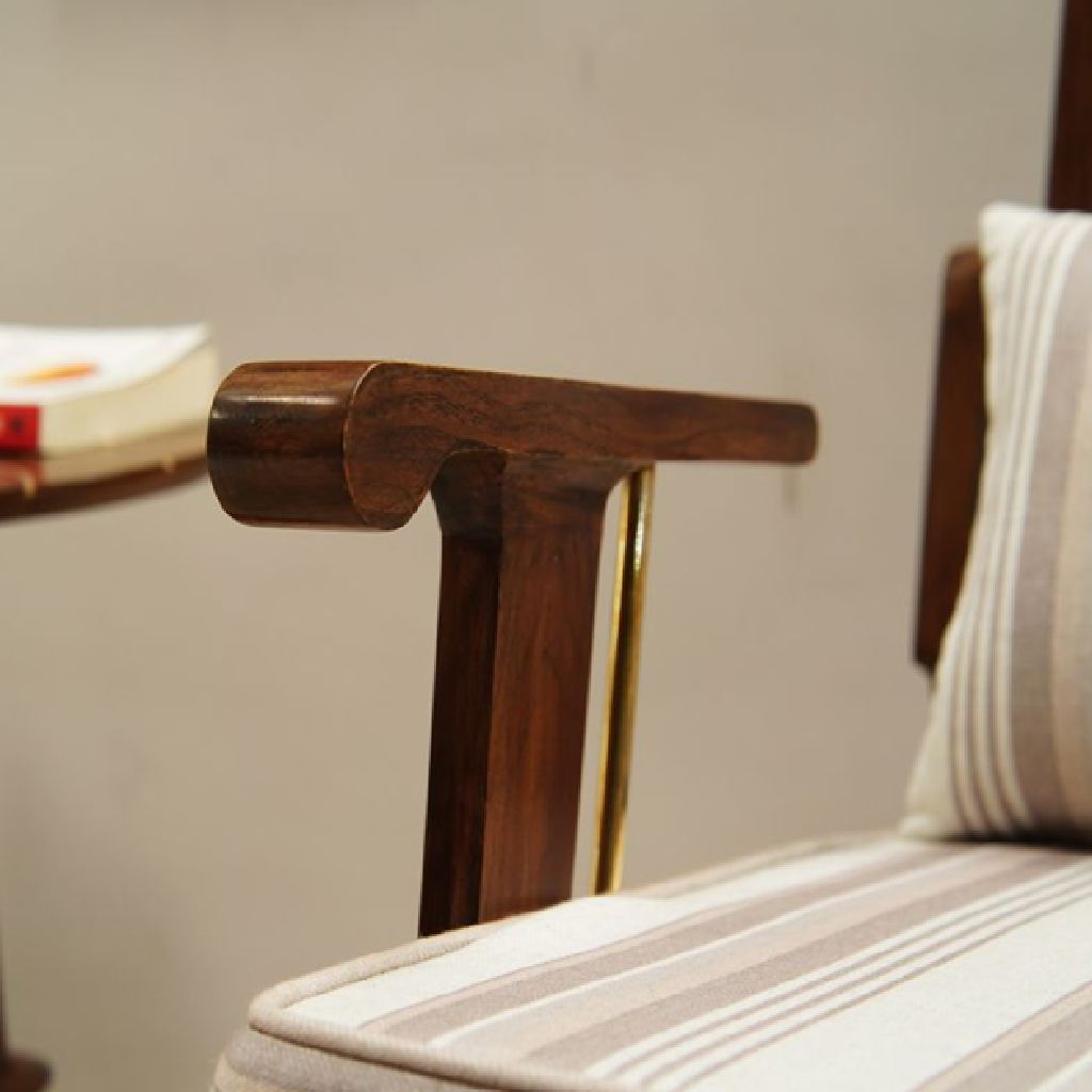 Close-up of a wooden armchair with striped cushion against a neutral wall.