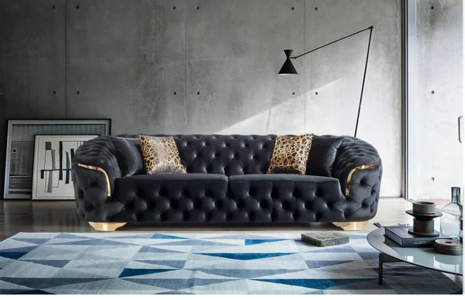 Modern living room with a black tufted sofa, geometric rug, and abstract art.