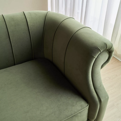 Green curved sofa in a room with light-colored curtains.
