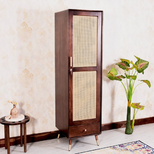 Wooden cabinet with wicker door in a room setting with a plant and small table.