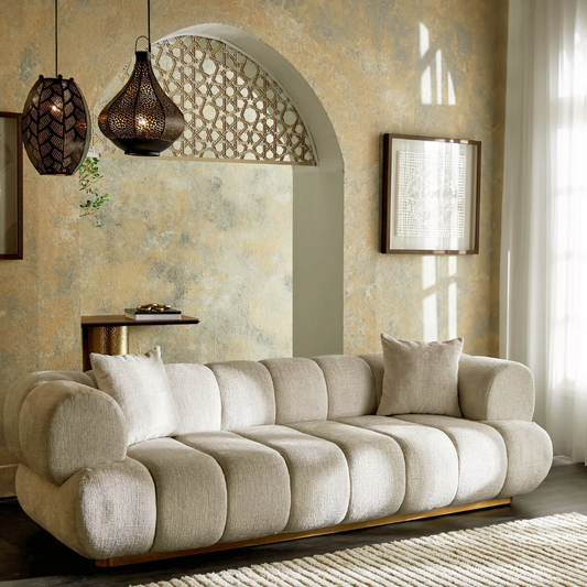 Modern living room with a beige sofa, decorative pillows, and hanging lamps.
